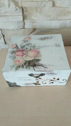 a white box with pink roses painted on the lid and bottom is sitting on a table