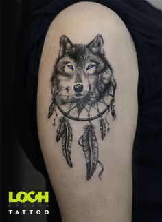 a wolf tattoo on the left arm with feathers and dream catcher in front of it