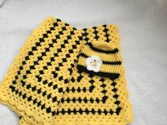 a yellow and black crocheted blanket with a flower on it