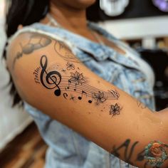 a woman with a tattoo on her arm has music notes and flowers all over it