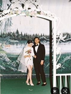 a man and woman standing in front of a wedding arch