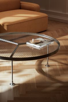 a coffee table with a book on it in the middle of a wooden floored room