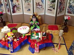 a doll sitting on top of a red table next to a cake and other decorations