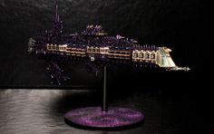 a lego model of a purple ship on top of a black table with a dark background