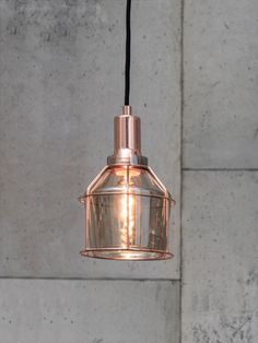 a light that is hanging from a wire in a room with concrete wall behind it