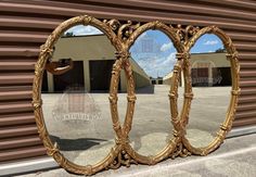 an ornate gold mirror is shown in front of a building