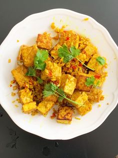 a white plate topped with tofu covered in sauce and garnished with cilantro