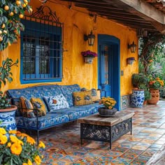 a blue and yellow couch sitting on top of a patio next to potted plants