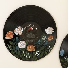 two records with flowers painted on them are next to each other in front of a wall