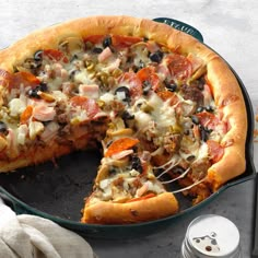 a pizza sitting on top of a pan covered in cheese and toppings with one slice missing