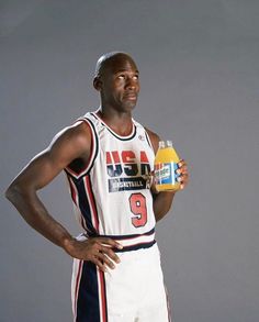 a basketball player holding a bottle of juice and looking at the camera with his hands on his hips