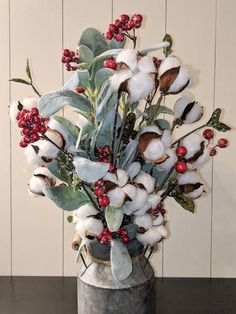 a vase filled with cotton and berries on top of a table