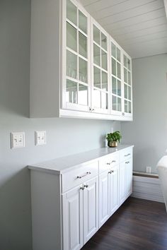 a kitchen with white cabinets and wood flooring next to a wall mounted light switch