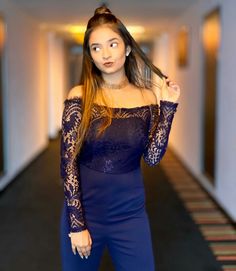 a woman in a blue jumpsuit posing for the camera with her hair blowing back