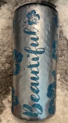 a can of soda with blue glitters on it sitting on a carpeted floor