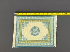 a piece of cloth with a blue and yellow design on it next to a ruler