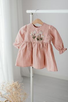 Introducing our beautiful Pink Linen Dress, the perfect addition to any little girl's wardrobe! Made from the finest, soft linen material, this dress is both comfortable and stylish, making it perfect for a variety of occasions. Featuring delicate, hand embroidered daisy flowers on the chest, this dress is the perfect choice for a baby shower gift, christening dress, baby wedding dress, or even a flower girl dress for weddings. The long sleeve design with ruffle adds a touch of elegance to the dress, making it perfect for a 1st birthday celebration or baptism. This stunning dress is also perfect for the spring season, making it a great choice for a toddler spring dress. The linen material is breathable and lightweight, keeping your little one comfortable in warmer weather. Each dress is ha Embroidered Long Sleeve Linen Dress For Spring, Spring Linen Dress With Embroidered Hem, Linen Dresses For Spring Baptism, Long Sleeve Cotton Dress With Floral Embroidery, Pink Long Sleeve Dress With Embroidered Hem, Cute Cotton Embroidered Spring Dress, Cute Spring Embroidered Cotton Dress, Spring Embroidered Linen Dress, Spring Baptism Cotton Dress