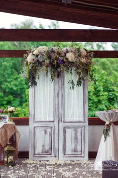 an outdoor wedding setup with flowers and greenery on the doors, table cloths and chairs