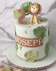 a birthday cake with a lion on top and jungle leaves around the edges, sitting on a marble table