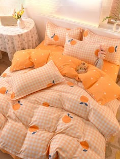 a bed with orange and white checkered bedspread, teddy bear on the pillow