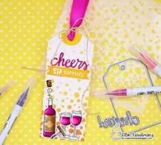 some pens and markers are sitting on a yellow tablecloth with wine tags attached to them