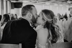 a bride and groom kissing each other in front of an audience at a wedding reception