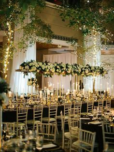 the tables are set up with white flowers and candles for an elegant dinner or reception