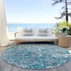 a living room area with a couch and rug on the floor next to an ocean view