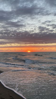 the sun is setting over the ocean with waves coming in