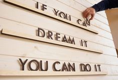 a man is placing letters on the side of a building that says, if you can dream it, dream it, you can do it