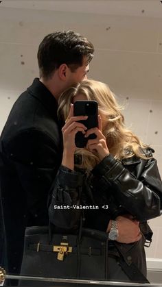 a man and woman taking a selfie in front of a mirror with their cell phone