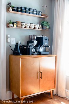 a wooden cabinet with coffee pots and cups on it