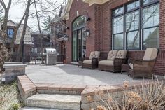 an outdoor patio with chairs and steps leading up to the front door, next to a brick building