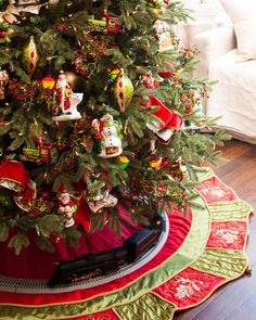 a christmas tree is decorated with ornaments and train tracks