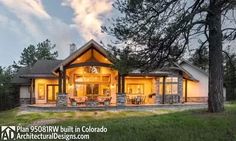 a large house sitting on top of a lush green field next to a forest filled with trees