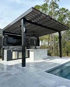 an outdoor bbq with grill and sink next to a swimming pool