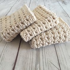 three crocheted dishcloths sitting on top of a wooden table