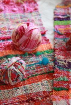 some balls of yarn are laying on top of a piece of knitted material, which is multicolored