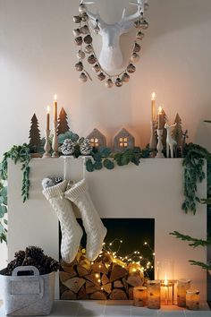 a fireplace decorated for christmas with candles and stockings hanging from it's mantel