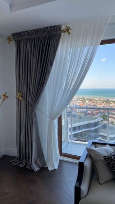 a living room filled with furniture and a large window covered in white curtained drapes