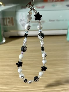 a pair of black and white beads hanging from a chain on a table next to a pen