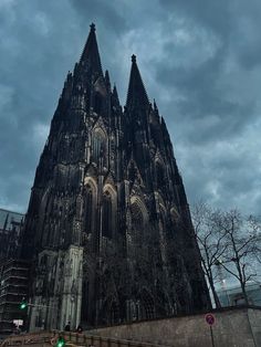 a very tall cathedral towering over a city under a cloudy sky with traffic lights on it