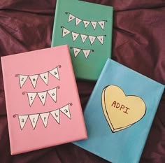 three painted canvass with hearts and bunting on them, one has an applique