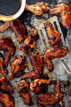 barbecue chicken wings with sauce on the side next to a fork and cup of coffee