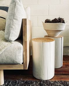 two wooden stools sitting next to each other on top of a wood floor near a couch