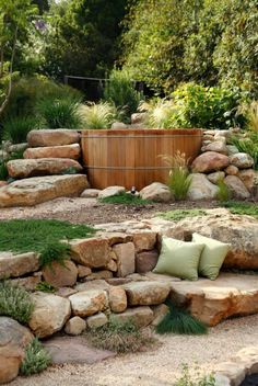 an outdoor hot tub surrounded by rocks and plants