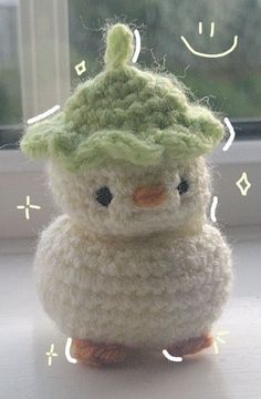 a small crocheted bird sitting on top of a table next to a window