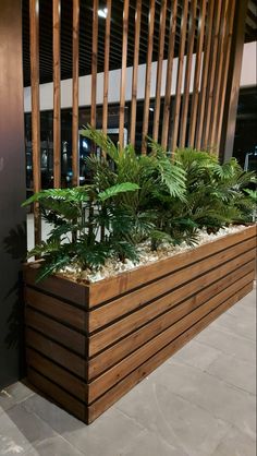 a planter filled with lots of green plants on top of a wooden bench next to a wall