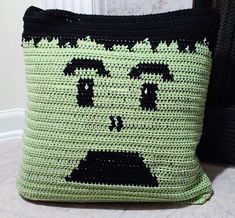 a crocheted green and black pillow sitting on top of a floor