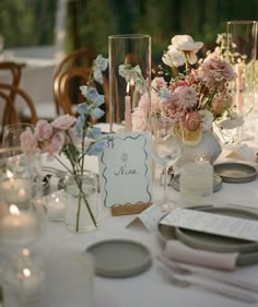 the table is set with flowers and place cards